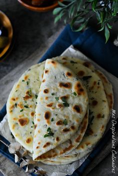 three flat breads sitting on top of a blue tray next to a potted plant