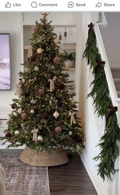 a decorated christmas tree sitting on top of a wooden floor next to a stair case