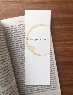 an open book with the words once upon a time printed on it next to some folded books