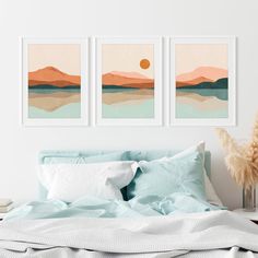 two paintings on the wall above a bed in a room with white walls and blue sheets