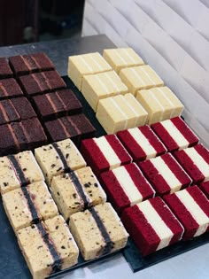 several different types of desserts are displayed on a table with white and red frosting