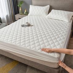 a person reaching for a mattress on the floor