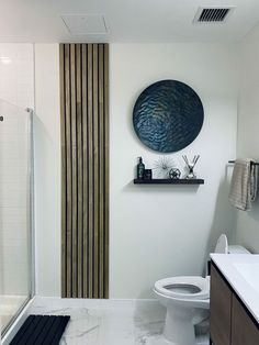 a bathroom with a toilet, sink and shower in it's own area that has a wooden panel on the wall