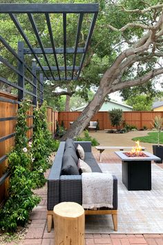 an outdoor living area with couches, tables and a fire pit in the middle