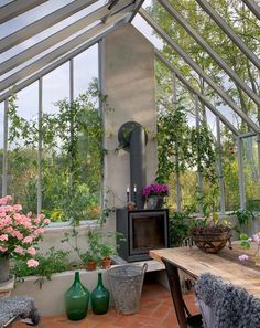 a room filled with lots of plants and flowers inside of a glass roofed building