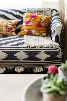 a couch with colorful pillows on it next to a potted plant