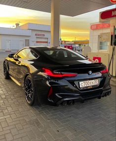 a black sports car parked in front of a gas station