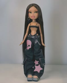 a doll with long black hair and pink stars on it's pants, is posed in front of a gray background