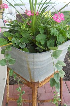 a potted plant sitting on top of a metal stand with pink flowers in it