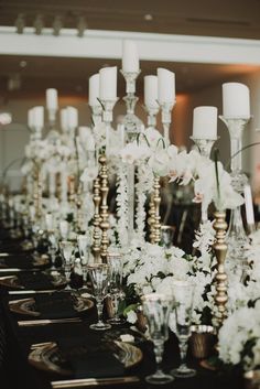 a long table topped with lots of white flowers and candles