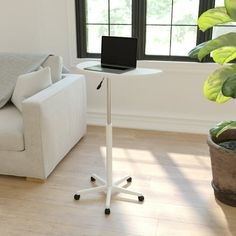 a laptop computer sitting on top of a white table next to a couch in a living room