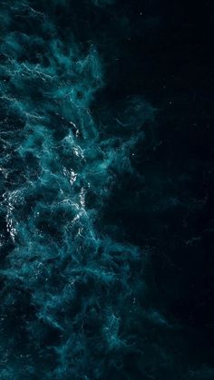 an aerial view of the ocean with dark blue water and white bubbles on it's surface