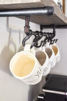 three coffee mugs hanging from a shelf