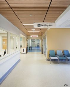 an empty waiting area with blue chairs in the foreground and a sign that reads waiting area