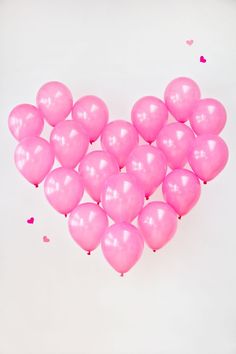 pink heart shaped balloons on white background with confetti