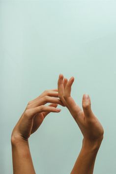 two hands reaching up into the air to catch a frisbee