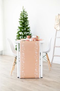 the table is set up with two white chairs and a small christmas tree in the background