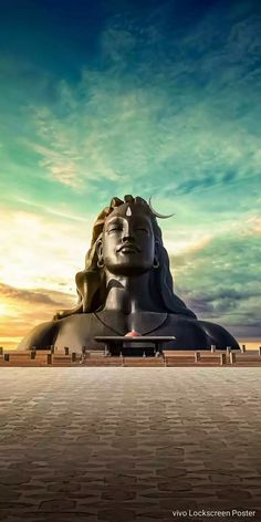 a large buddha statue sitting on top of a brick floor under a blue sky with clouds