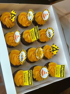 cupcakes with yellow frosting are arranged in a white box on a table