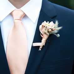 a man in a suit with a pink tie and boutonniere