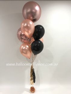 a bunch of balloons with tassels hanging from the ceiling in front of a white wall