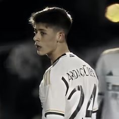 a young man standing next to another person wearing a white shirt and black lettering on it