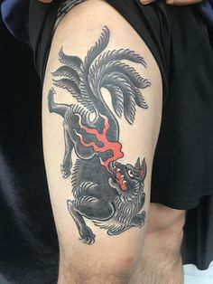 a man with a black and red tattoo on his arm is holding onto the back of his leg