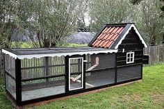 a black chicken coop with a red roof and white trim on the top is shown