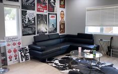 a living room filled with black furniture and pictures on the wall above it's coffee table