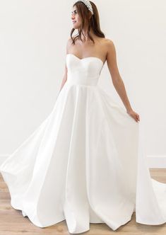 a woman in a white wedding dress standing on a wooden floor with her back to the camera