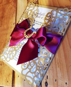 a box with a red bow on it sitting on a wooden table next to a piece of paper