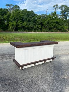 a large white box sitting on top of a parking lot next to a lush green field