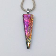 This fused glass pendant has beautiful pink and gold dichroic glass with a purple shift in a starburst textured pattern. The color shifts and sparkle of the texture are amazing and truly gorgeous! This triangle shaped pendant measures 48mm (1 7/8") long by 17mm (5/8") wide and is mounted on a silver plated bail.  ** Included is a complimentary necklace of your choice. You can see the full descriptions of your choices in this section of my shop: https://www.etsy.com/shop/AngelasArtGlass?section_id=13300327 This pendant will arrive in a gift box ready for gift giving. The true beauty of dichroic glass is difficult to capture in a photo. The color shifts at various angles and lighting can be quite amazing. You will truly appreciate the depth and sparkle of this lovely pendant when you see it Dichroic Jewelry, Dichroic Pendant, Starburst Necklace, Dichroic Glass Pendant, Yellow Necklace, Fused Glass Pendant, Fused Glass Jewelry, Dichroic Glass, Glass Jewelry