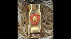 a gold vase with a red star on it in a box filled with shredded paper