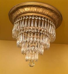 a chandelier hanging from the ceiling in a room with yellow walls and gold trim