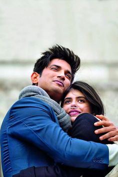 a man and woman hugging each other in front of a building