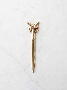 a gold fox head brooch pin on a white marble surface with a black cat's eye