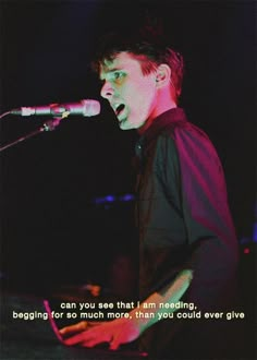 a man standing in front of a microphone on top of a stage next to a keyboard