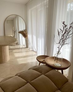 a living room filled with furniture and a large mirror on top of the wall next to a window