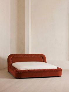 an orange couch sitting on top of a hard wood floor next to a white wall