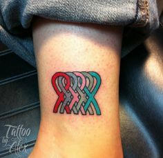 a tattoo on the foot of a woman with two intertwineded hearts in red, blue and green