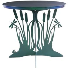 a metal table with dragonflys and flowers on the top, sitting in front of a white background