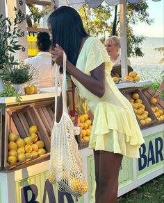 a woman standing in front of a fruit stand with lemons on it's display