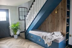 a room with a wooden floor and blue painted stairs, next to a white door