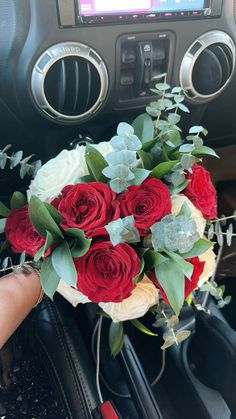 a bouquet of red and white roses sitting on top of a car dashboard next to a radio