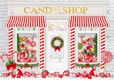 a candy shop with red and white striped awnings, wreaths and christmas decorations