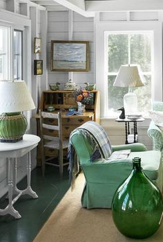 a living room filled with furniture and lots of green decor on top of carpeted flooring