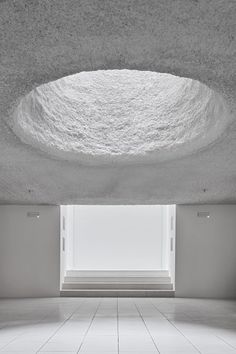 an empty room with white tile floors and a skylight in the center is shown