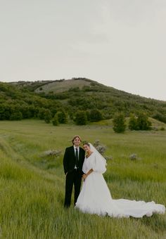 a bride and groom standing in the middle of a field