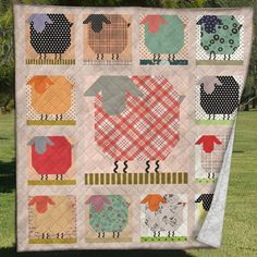 a patchwork quilt with sheeps on it in the middle of a grassy field